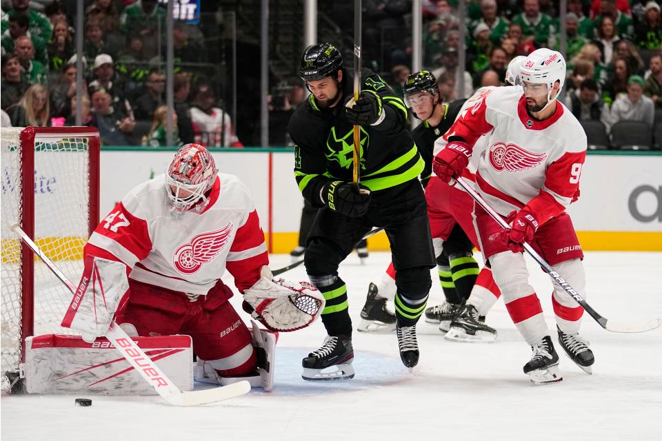 Red Wings goaltender James Reimer looks down at the puck as center Joe Veleno helps defend the net against pressure from Stars left wing Jamie Benn in the first period on Monday, Dec. 11, 2023, in Dallas.