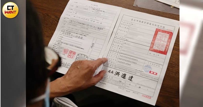 陳先生指著母親的死亡證明書及火化許可證，死因都是「新冠肺炎併心肺衰竭」，但衛生單位卻不認可。（圖／李宗明攝）