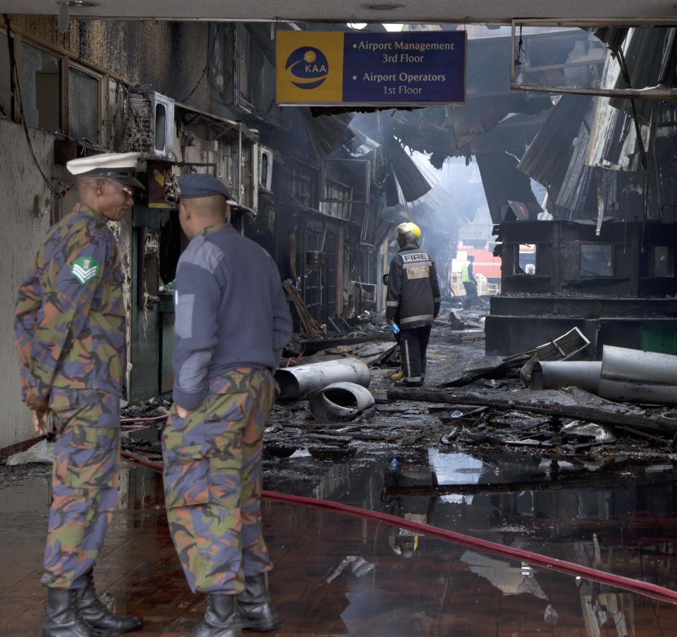 Kenya Airforce personnel view the damage after fire engulf the international arrivals area of Jomo Kenyatta International Airport, Nairobi, Kenya, Wednesday, Aug. 7, 2013. A massive fire engulfed the arrivals hall at Kenya's main international airport early Wednesday, forcing East Africa's largest airport to close and the rerouting of all inbound flights. (AP Photo/Sayyid Azim)