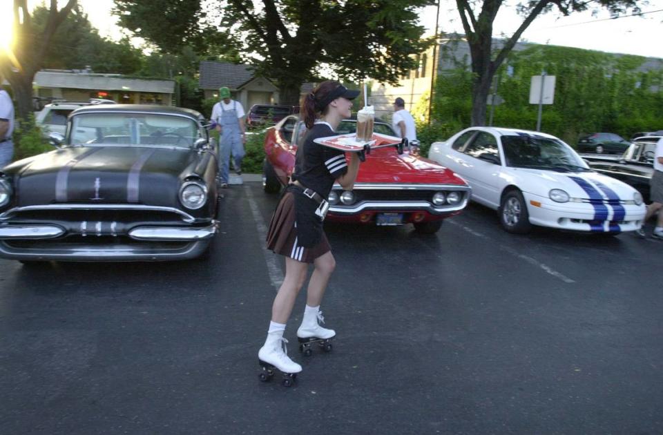Sara Gallagher, 16, from Modesto roller skates by some cars from Pharoahs car club on her way to deliver a rootbeer float at A&W Root Beer at 14th and G Streets in Modesto.