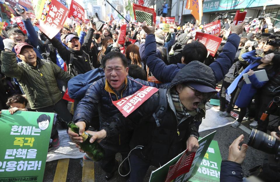 Protesters open a bottle of champagne to celebrate during a rally calling for impeachment of President Park Geun-hye near the Constitutional Court in Seoul, South Korea, Friday, March 10, 2017. In a historic ruling Friday, South Korea's Constitutional Court formally removed the impeached president from office over a corruption scandal that has plunged the country into political turmoil, worsened an already-serious national divide and led to calls for sweeping reforms. (AP Photo/Lee Jin-man)