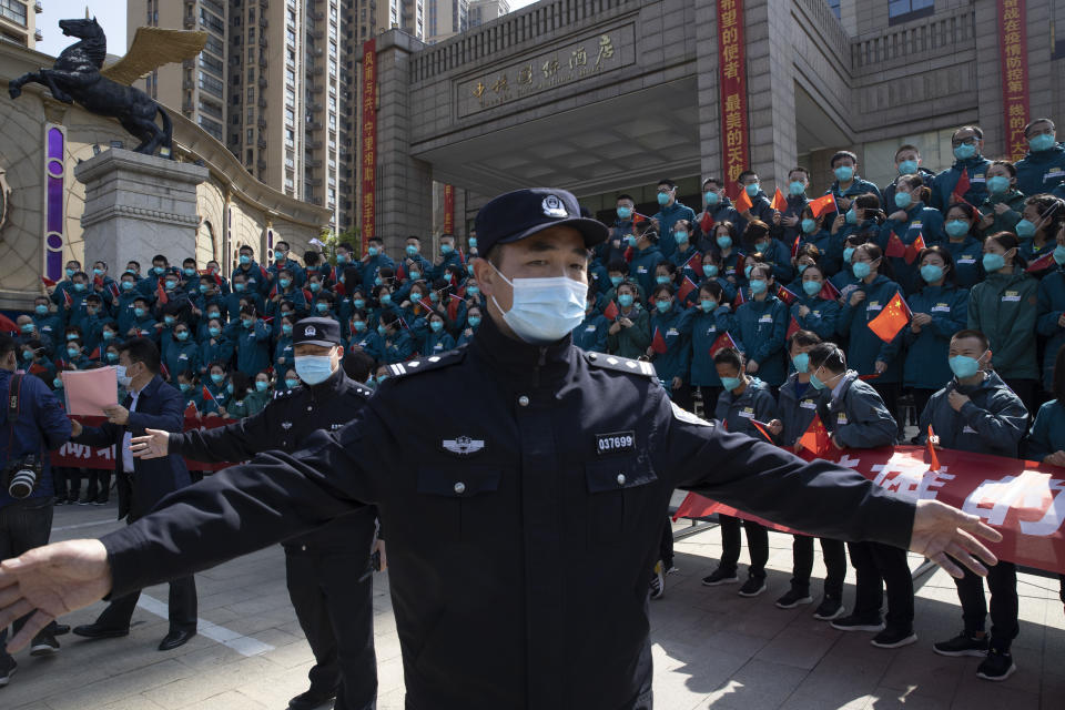 FILE - A policeman moves journalists back from a farewell event held for the last group of medical workers who came from outside Wuhan to help the city during the coronavirus outbreak in Wuhan in central China's Hubei province on April 15, 2020. The hunt for COVID-19 origins has gone dark in China. An AP investigation drawing on thousands of pages of undisclosed emails and documents and dozens of interviews found feuding officials and fear of blame ended meaningful Chinese and international efforts to trace the virus almost as soon as they began, despite years of public statements to the contrary. (AP Photo/Ng Han Guan, File)