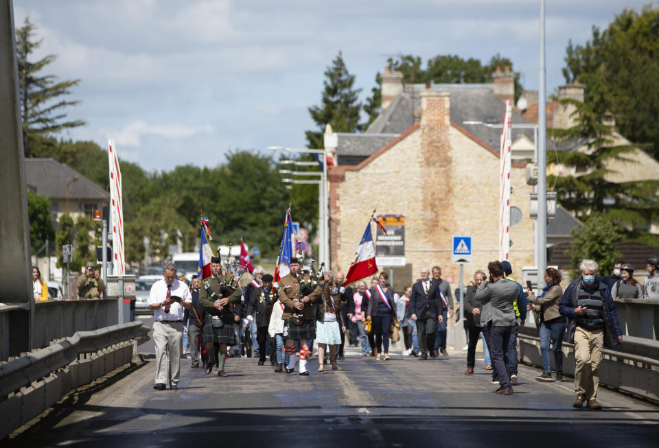 British expatriate Steven Oldrid, left, prepares to film a group crossing over the site of the original WWII Pegasus Bridge during D-Day ceremonies in Benouville, Normandy, France on Saturday, June 6, 2020. Due to coronavirus measures many relatives and veterans will not make this years 76th anniversary of D-Day. Oldrid will be bringing it to them virtually as he places wreaths and crosses for families and posts the moments on his facebook page. (AP Photo/Virginia Mayo)