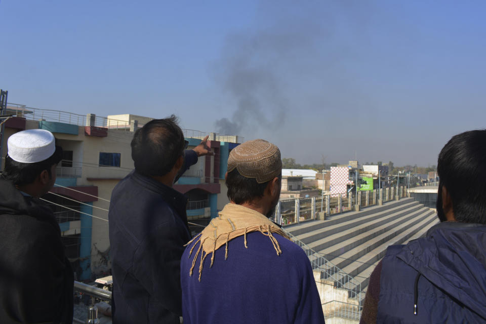 Local residents watch smoke rising from a counter-terrorism center after security forces starting to clear the compound seized earlier by Pakistani Taliban militants in Bannu, a northern district in the Pakistan's Khyber Pakhtunkhwa province, Tuesday, Dec. 20, 2022. Pakistan's special forces on Tuesday stormed a counter-terrorism center in the remote northwest district to free several security officials who were taken hostage earlier this week by a group of detained Pakistani Taliban militants, security officials said. (AP Photo/Muhammad Hasib)