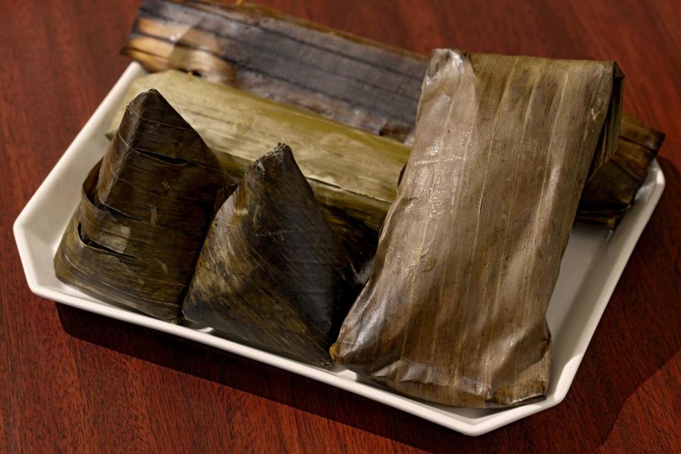 Assorted shapes of banana-leaf-wrapped sticky rice cakes on a plate.