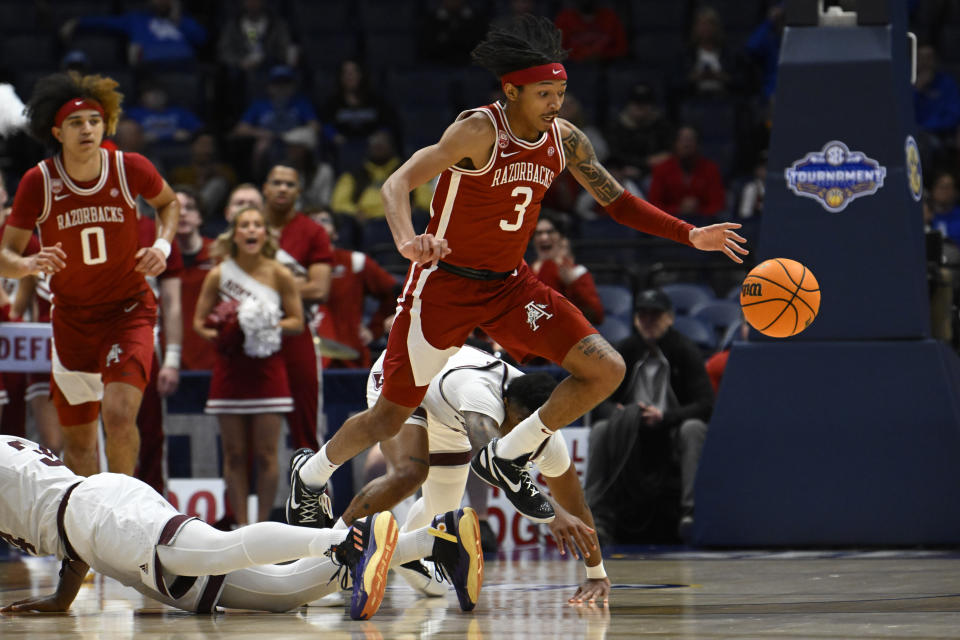 Arkansas guard Nick Smith Jr. (3) jumps over Texas A&M forward Julius Marble to chase the ball during the first half of an NCAA college basketball game in the quarterfinals of the Southeastern Conference Tournament, Friday, March 10, 2023, in Nashville, Tenn. (AP Photo/John Amis)