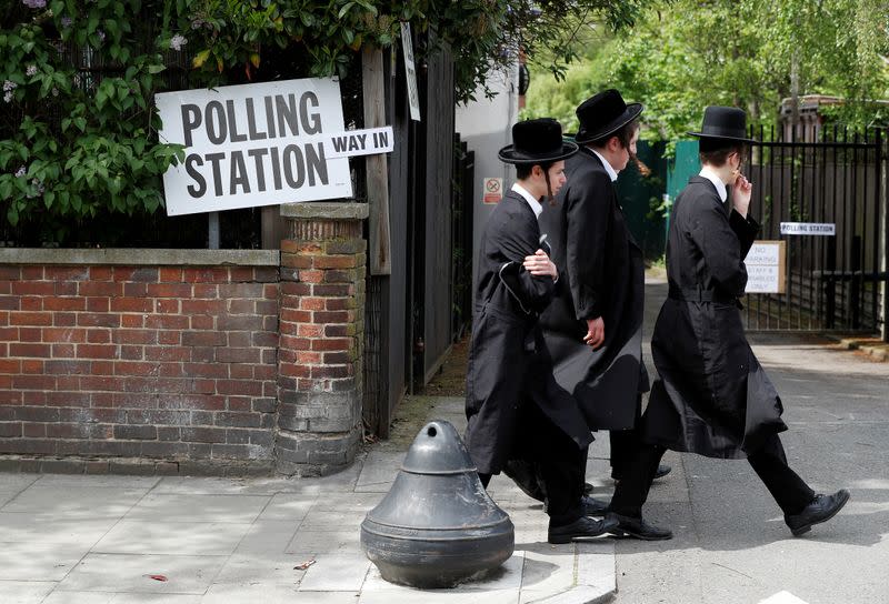 FILE PHOTO: Orthodox Jewish men walk past a polling station during local government elections in the Stamford Hill area of London
