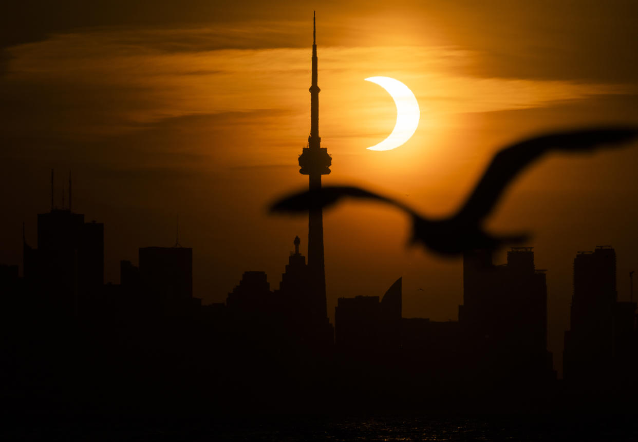 The sun rises behind the skyline during an annular eclipse on June 10, 2021 in Toronto, Canada. On April 8, people will be travelling from all around the world to catch a glimpse of the solar eclipse. (Photo by Mark Blinch/Getty Images)