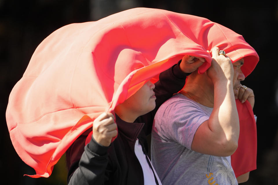 A man and woman use a cloth over their heads to protect them from the sun in Manila, Philippines on Monday, April 29, 2024. Millions of students in all public schools across the Philippines were ordered to stay home Monday after authorities cancelled in-person classes for two days as an emergency step due to the scorching heat and a public transport strike. (AP Photo/Aaron Favila)