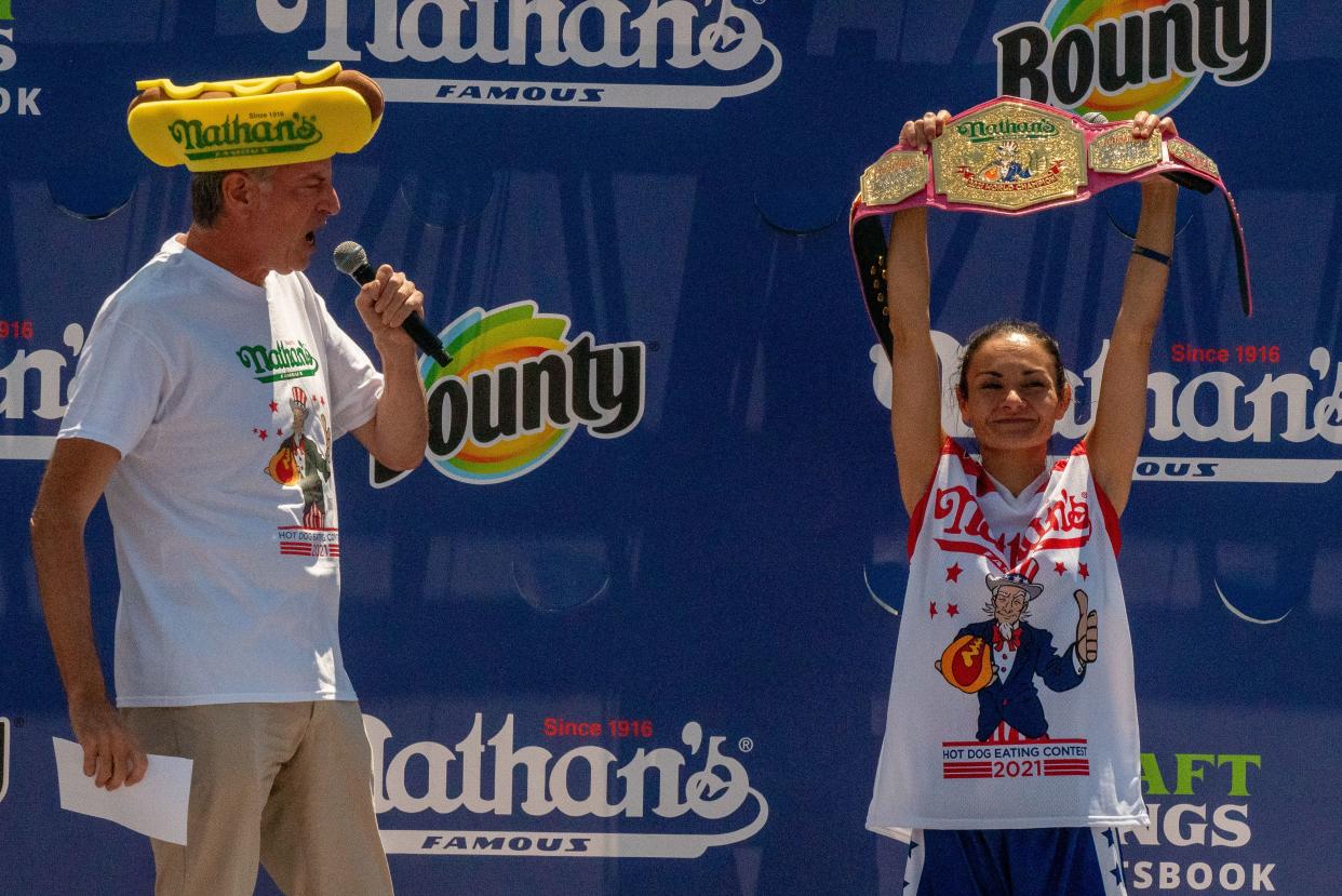 New York City Mayor Bill De Blasio presents the championship belt to Michelle Lesco at the women's 2021 Nathan's Famous 4th Of July International Hot Dog Eating Contest on July 4, 2021, in New York City.