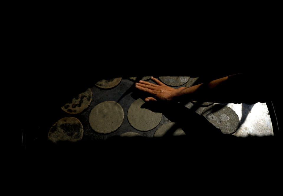 A woman cooks native purple corn tortillas on a comal or griddle at a restaurant in Apizaco, Mexico, Thursday, May 18, 2023. Some Mexican farmers are finding a niche but increasing market among consumers seeking organic produce from small-scale growers and chefs worldwide. (AP Photo/Fernando Llano)