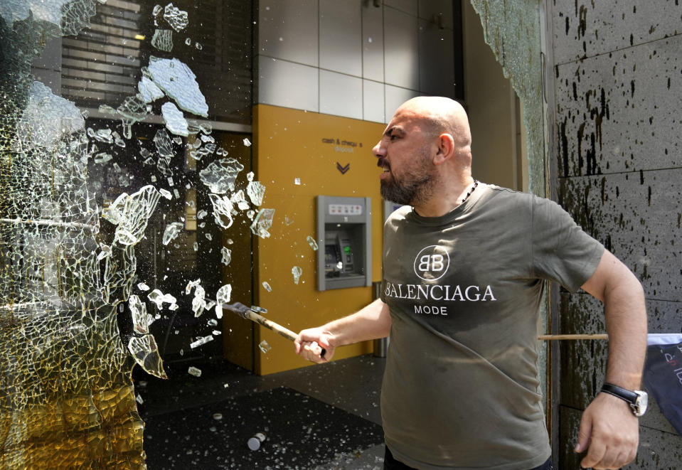 FILE - A man smashes windows at Byblos Bank during a protest demanding the release of depositors' trapped savings, in Beirut, Lebanon, Thursday, June 15, 2023. Four years into Lebanon's historic economic meltdown, Lebanon's elites are pushing an economic recovery plan that would sidestep critical reforms demanded by the International Monetary Fund. (AP Photo/Hussein Malla, File)