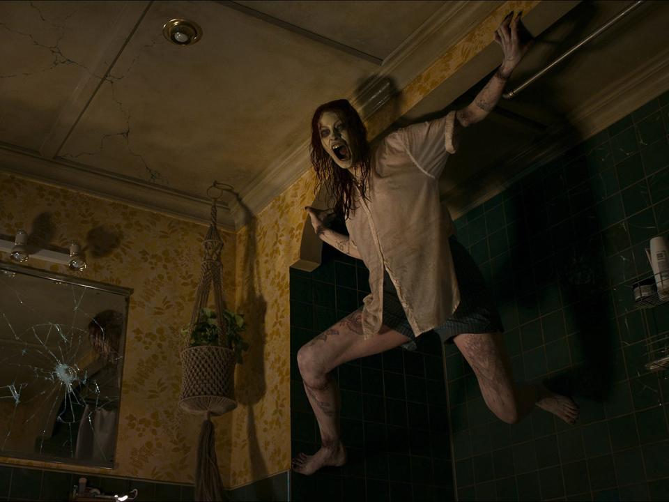 Alyssa Sutherland as deadite Ellie in the corner of the bathroom in "Evil Dead Rise."