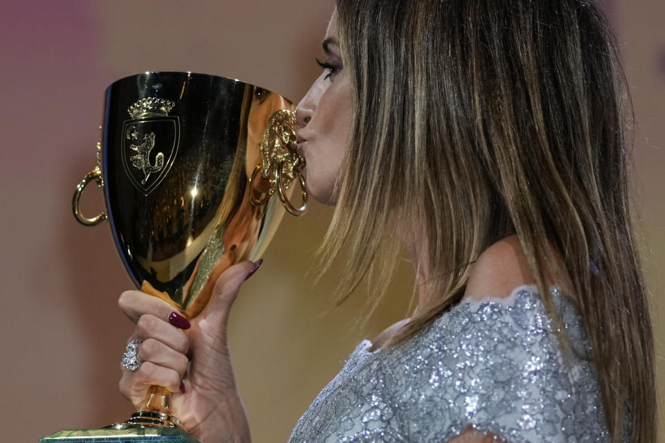 Penelope Cruz kisses the Coppa Volpi Best Actress award for 'Parallel Mothers' onstage at the closing ceremony during the 78th edition of the Venice Film Festival in Venice, Italy, Saturday, Sept. 11, 2021. (AP Photo/Domenico Stinellis)