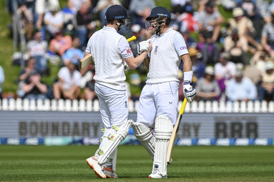 Joe Root, right, of England and Harry Brook celebrate their 200 run partnership on the first day of the second cricket test against New Zealand at the Basin Reserve in Wellington, New Zealand, Friday, Feb. 24, 2023. (Andrew Cornaga/Photosport via AP)