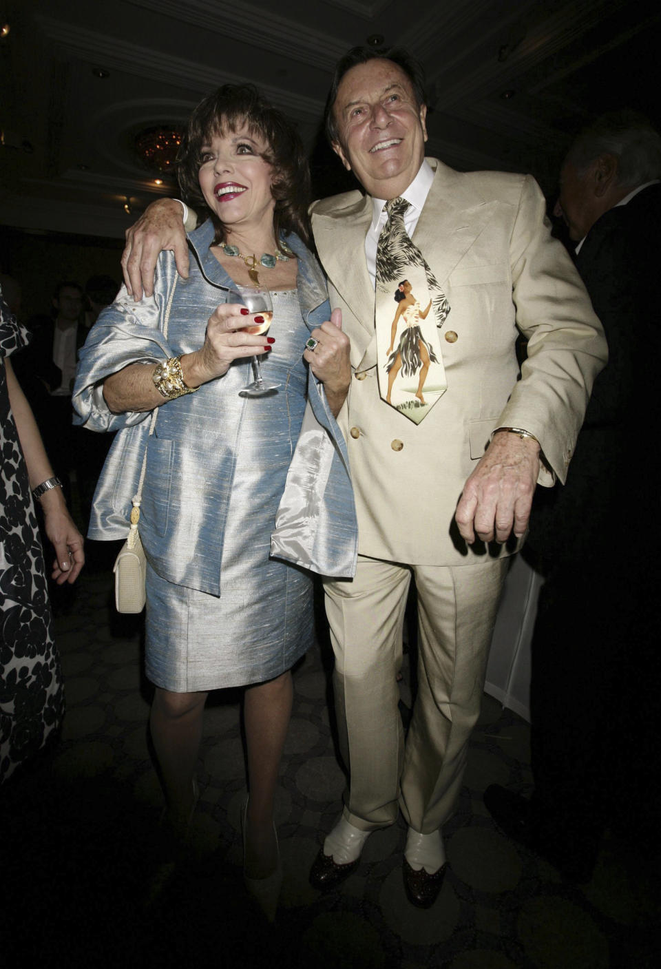 FILE - Actress Joan Collins and actor Barry Humphries pose during a party to celebrate the 180th Anniversary of weekly politics magazine The Spectator, held at the Churchill Hyatt Hotel in central London, May 7, 2008. Tony Award-winning comedian Barry Humphries, internationally renowned for his garish stage persona Dame Edna Everage, a condescending and imperfectly-veiled snob whose evolving character has delighted audiences over seven decades, has died on Saturday, April 22, 2023, after spending several days in a Sydney hospital with complications following hip surgery, a Sydney hospital said. (Yui Mok/PA via AP, File)