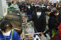 People wearing masks buy foods at a supermarket in Hangzhou in east China's Zhejiang province, Saturday, Feb. 8, 2020. China's communist leaders are striving to keep food flowing to crowded cities despite anti-disease controls, to quell fears of possible shortages and stave off price spikes from panic buying after most access to Wuhan was cut off Jan. 23. Food stocks in supermarkets ran low shortly after Beijing imposed travel curbs and extended the Lunar New Year holiday to keep factories, offices and other businesses closed and the public at home, attempting to prevent the virus from spreading. (Chinatopix via AP)