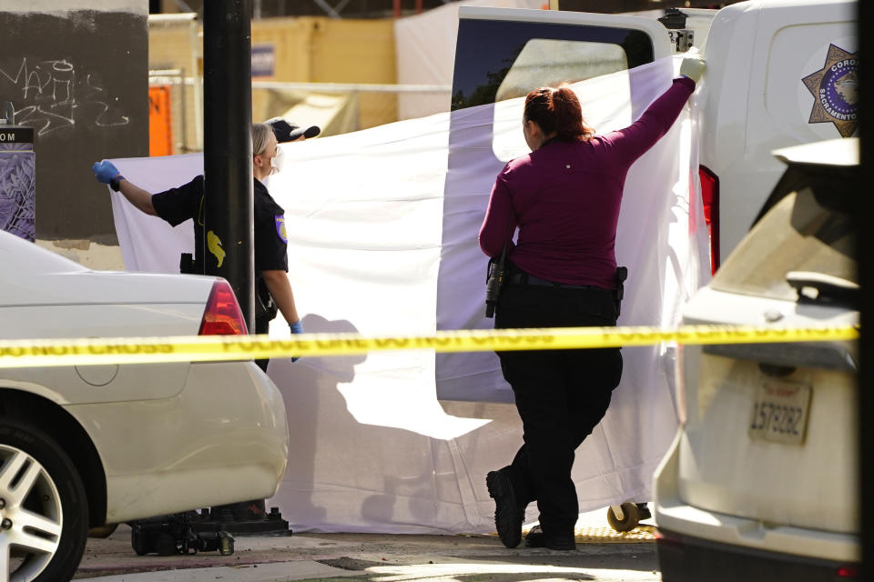 A sheet is used to block the view as the body of one of victims killed in a mass shooting is loaded into a coroners van In Sacramento, Calif. April 3, 2022. (AP Photo/Rich Pedroncelli)