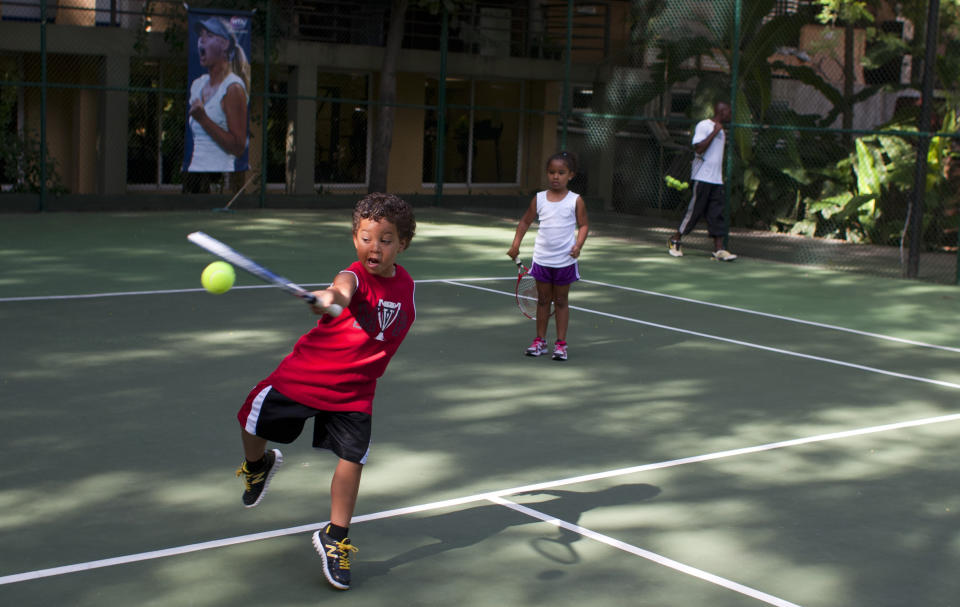 In this July 3, 2013 photo, Teo Biamby 4, swats a tennis ball as Kaden, his 5-year-old sister watches, while on summer vacation with their parents, at the Karibe Hotel in Port-au-Prince, Haiti. Haiti tourism is a tough sell not just because of its history of political unrest or because it was designated by the U.S. State Department in 2012 as a “major drug trafficking country.” It’s also difficult to sell because its Caribbean neighbors are cheaper; hotels are relatively expensive and fees such as generator fuel and potable water are often included in room rates. (AP Photo/Dieu Nalio Chery)