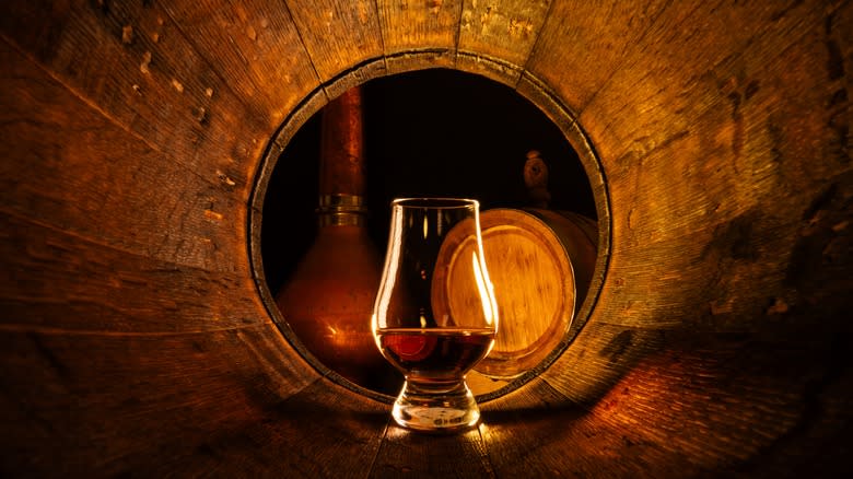 Glass of whiskey in barrel