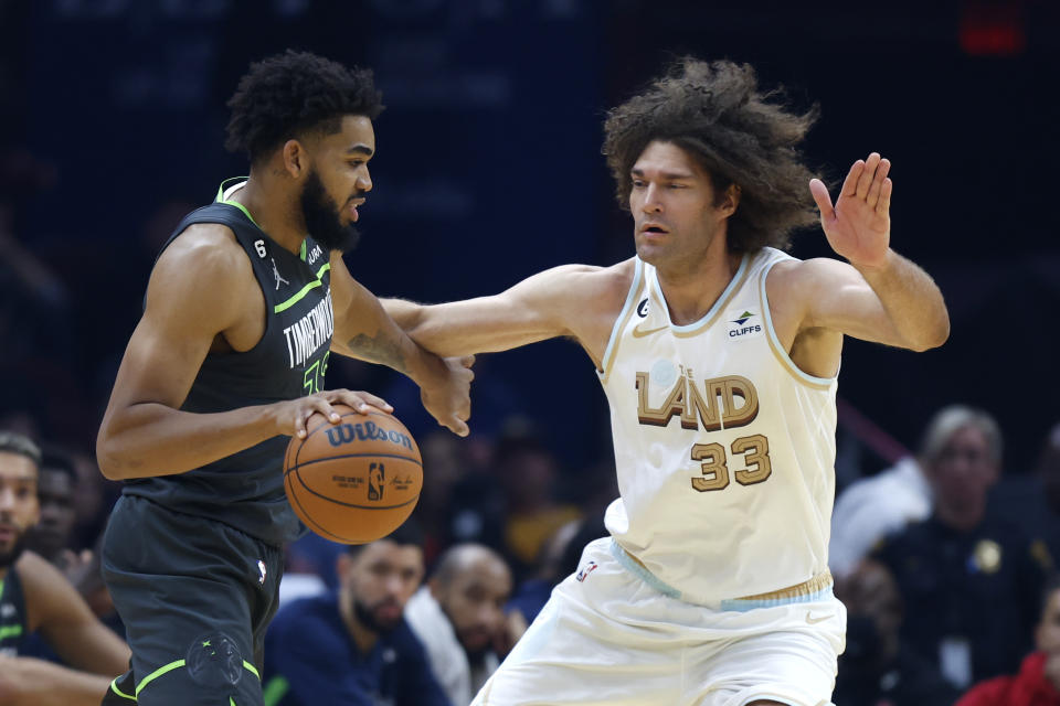 Minnesota Timberwolves center Karl-Anthony Towns (32) drives against Cleveland Cavaliers center Robin Lopez (33) during the first half of an NBA basketball game, Sunday, Nov. 13, 2022, in Cleveland. (AP Photo/Ron Schwane)