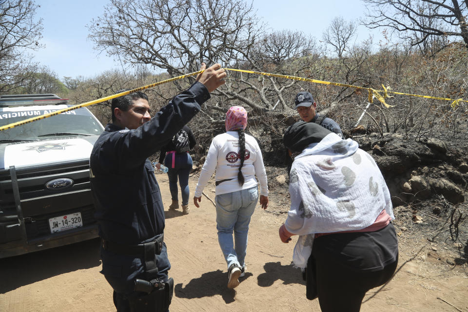 FILE - A police officer allows in members of the group Madres Buscadoras de Jalisco who found several sets of human remains after receiving an anonymous tip in Tlajomulco, Jalisco state, June 14, 2023. A drug cartel bomb attack on July 11, 2023 that allegedly used a fake report of a mass grave to lure police into a deadly trap has had devastating collateral damage: It has led authorities in Jalisco state to abandon the volunteers who search for some of Mexico’s 110,000 missing people. (AP Photo/Refugio Ruiz, File)