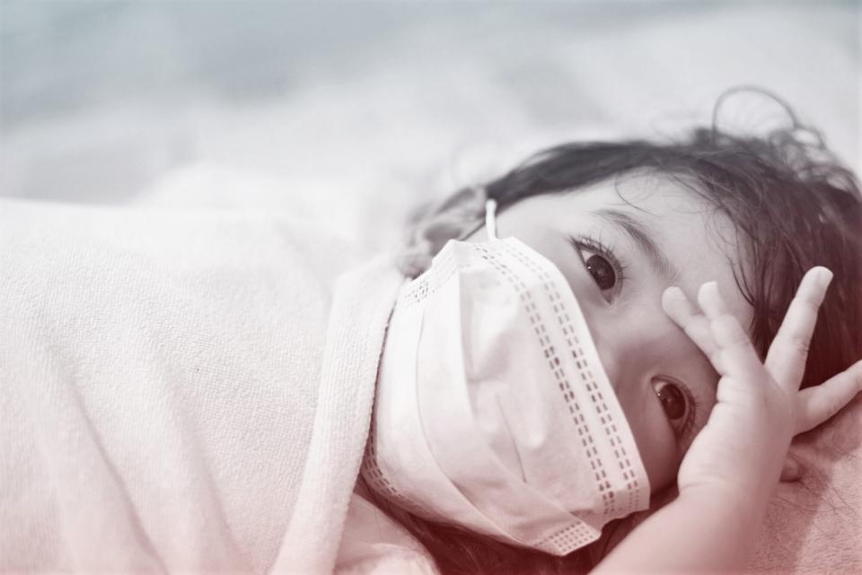 Young child wearing mask laying down not feeling well