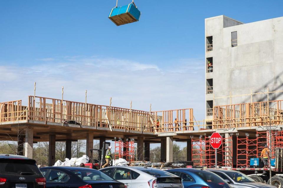 A large bundle of wood is hoisted over workers at a construction site in north Charlotte. No barricades were erected around the flatbed truck that the crane lifted the wood from.  