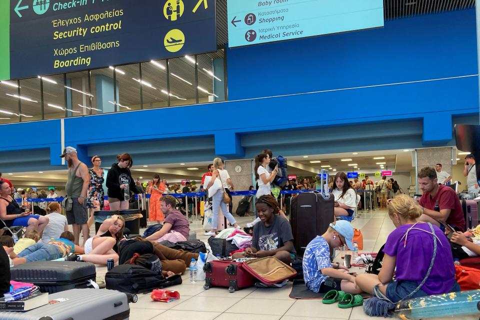 Tourists wait in the airport's departure hall as evacuations are underway due to wildfires, on the Greek island of Rhodes on July 23, 2023. Locals and tourists fled hotspots on Rhodes, as firefighters battled a blaze that had sparked the country's largest-ever fire evacuation. Firefighters were bracing for high winds that have been forecast for the afternoon and that could hamper their efforts. (Photo by Will VASSILOPOULOS / AFP) (Photo by WILL VASSILOPOULOS/AFP via Getty Images)