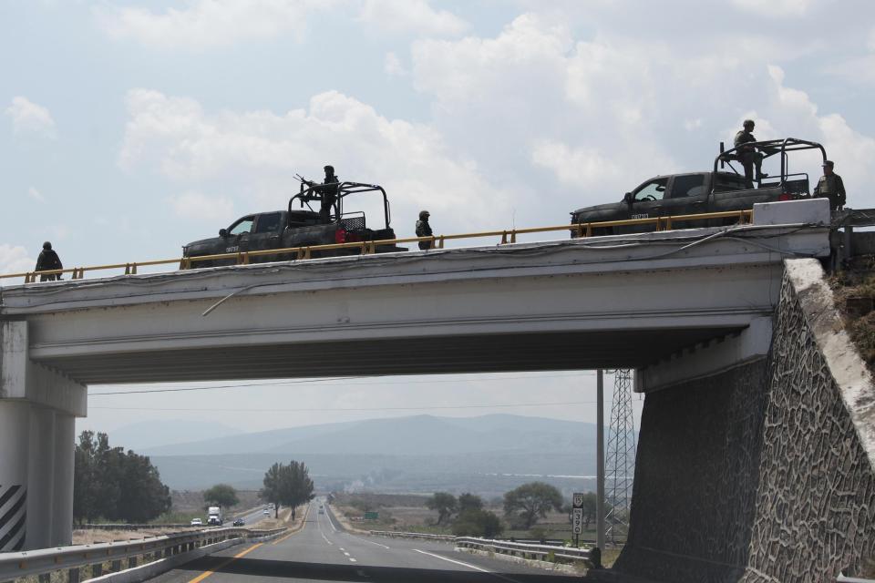 Members of Mexican Army stand guard in the highway bewteen Guadalajara in Jalisco state and Leon city, in Guanajuato State, Mexico, on May 01, 2015. More than a dozen vehicles were set on fire on Friday across Guadalajara, Mexico's second biggest city, while a drug gang and authorities clashed in another part of Jalisco state. Authorities have not said who was responsible for the violence, but it came amid an escalation of violence by the Jalisco New Generation Drug Cartel, which killed 20 police officers in two ambushes in March and April. AFP PHOTO/STR        (Photo credit should read STR/AFP via Getty Images)