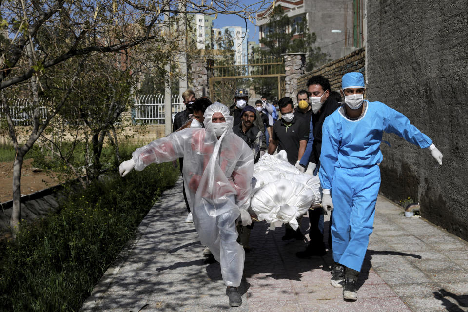 FILE - In this Monday, March 30, 2020 file photo, people carry the body of a victim who died after being infected with the new coronavirus at a cemetery just outside Tehran, Iran. Across the Middle East and parts of South Asia, bereaved families have faced traumatic restrictions on burying their dead amid the pandemic. Religion and customs that require speedy burials in the largely Muslim region have clashed with fears of COVID-19 contagion and government-mandated lockdowns. (AP Photo/Ebrahim Noroozi, File)