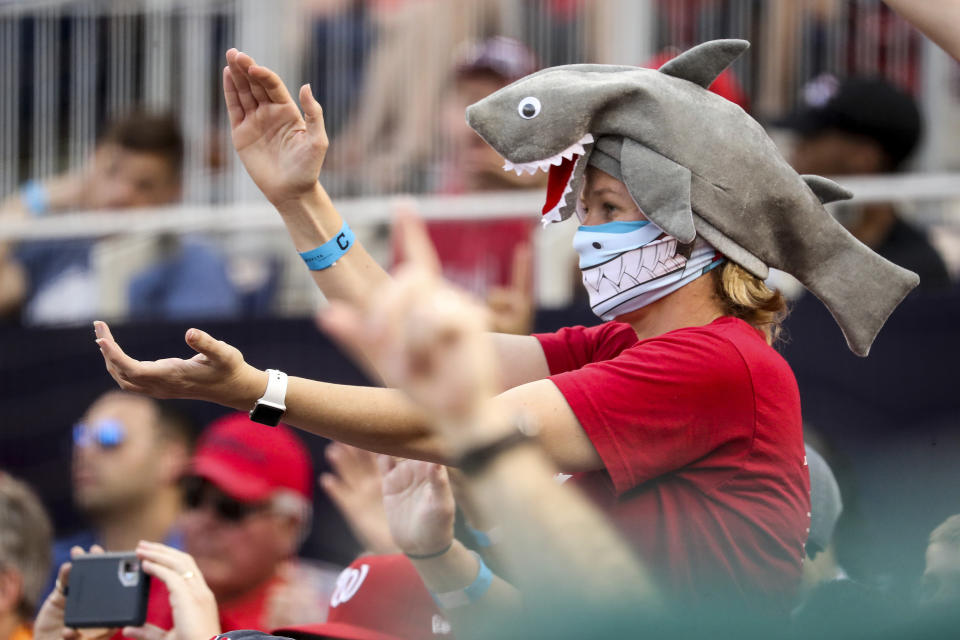 In this Sept. 29, 2019, file photo, a fan wears a shark hat as Washington Nationals' Gerardo Parra comes up to bat in the eighth inning of a baseball game against the Cleveland Indians at Nationals Park in Washington. Creators of the viral video “Baby Shark,” whose “doo doo doo” song was played at the World Series in October, are developing a version in Navajo. (AP Photo/Andrew Harnik, File)