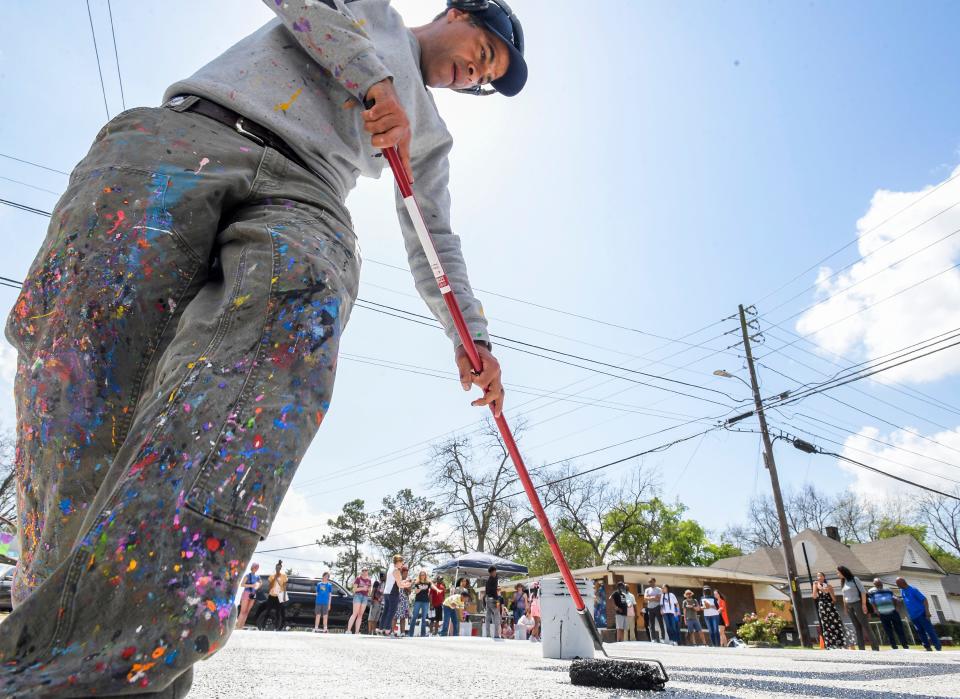 Artist JonOne begins painting a street mural at the intersection of Oak Street and Early Street during an Oak Street Block Party at King’s Canvas in Montgomery, Alabama, on Saturday, March 25, 2023.