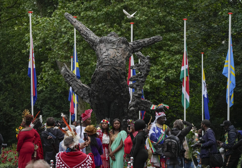 A white pigeon passes as people queue to pay their respect at the National Slavery Monument after Mayor Femke Halsema apologized for the involvement of the city's rulers in the slave trade during a nationally televised annual ceremony in Amsterdam, Netherlands, Thursday, July 1, 2021, marking the abolition of slavery in its colonies in Suriname and the Dutch Antilles on July 1, 1863. The anniversary is now known as Keti Koti, which means Chains Broken. Debate about Amsterdam's involvement in the slave trade has been going on for years and gained attention last year amid the global reckoning with racial injustice that followed the death of George Floyd in Minneapolis last year. (AP Photo/Peter Dejong)