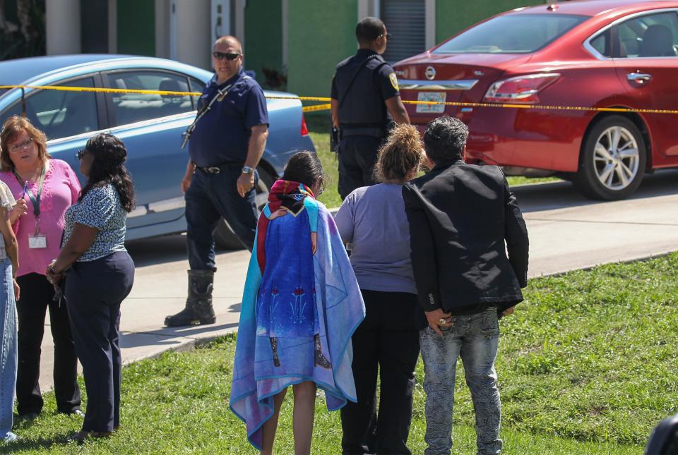 Family members (front center) watch the activities as St. Lucie County Fire District investigators search the remains of their house on Southwest Cactus Circle in Port St. Lucie. A 56-year-old man was found dead in the garage, police said. Fire District crews are investigating the cause of the blaze.