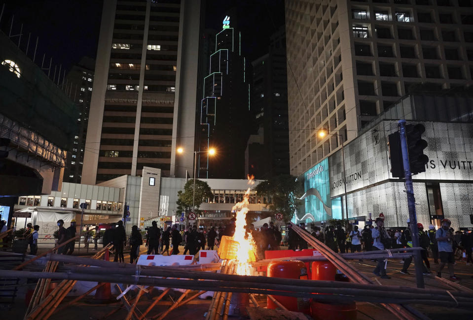 Demonstrators gather near a burning barricade in the street during a protest in Hong Kong, Saturday, Nov. 2, 2019. Anti-government protesters attacked the Hong Kong office of China's official Xinhua News Agency for the first time Saturday after chaos broke out downtown, with police and demonstrators trading gasoline bombs and tear gas as the protest movement approached the five-month mark. (AP Photo/Vincent Yu)