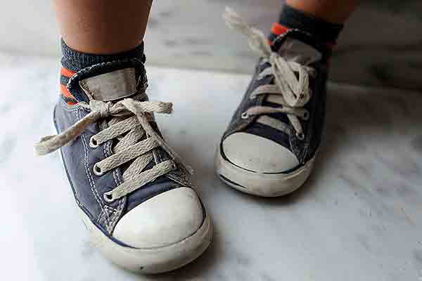 Un niño muestra su personal método para atarse los cordones de los zapatos. Foto: Westend61 / Getty Images.