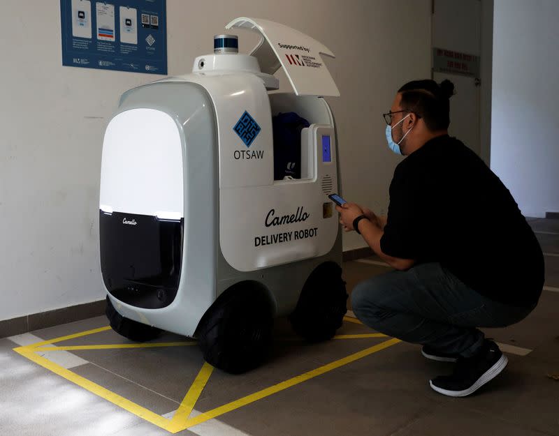 A customer collects his groceries from Carmello, an autonomous grocery delivery robot, in Singapore