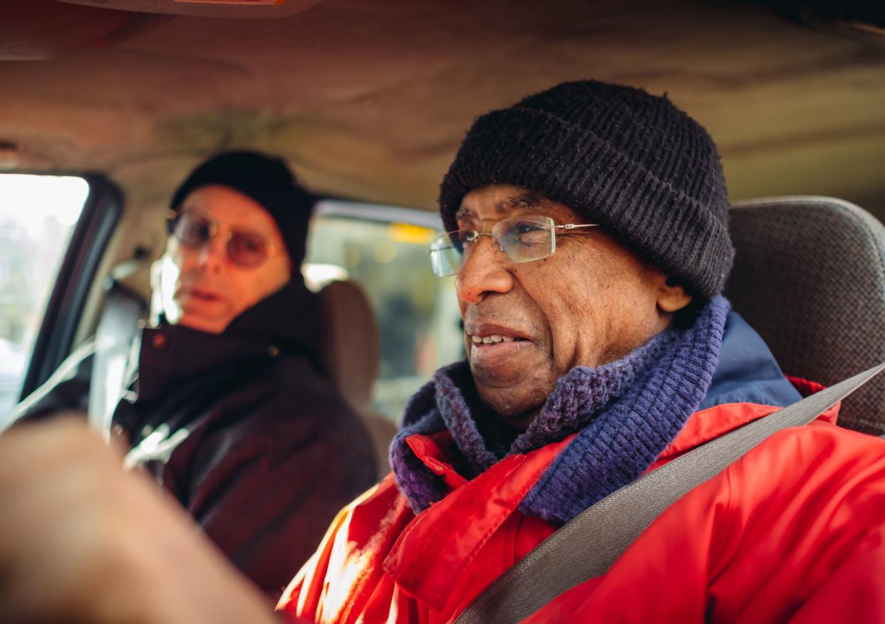 Two senior men driving in the mini van. Winter day with sunny weather.