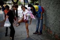 People cross over a barb wire used to block a side walk by opposition supporters during a rally against Venezuela's President Nicolas Maduro's government in Caracas, Venezuela, July 28, 2017. REUTERS/Andres Martinez Casares