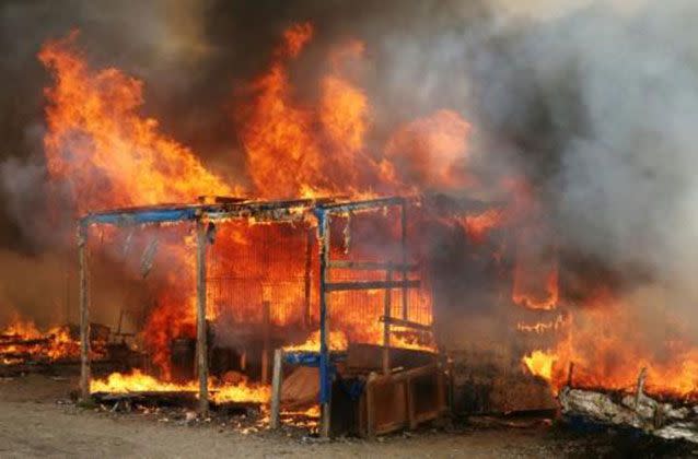 The abandoned slum outside the port of Calais smouldered from countless fires set by departing migrants, causing many to flee without their possessions. Picture: AFP