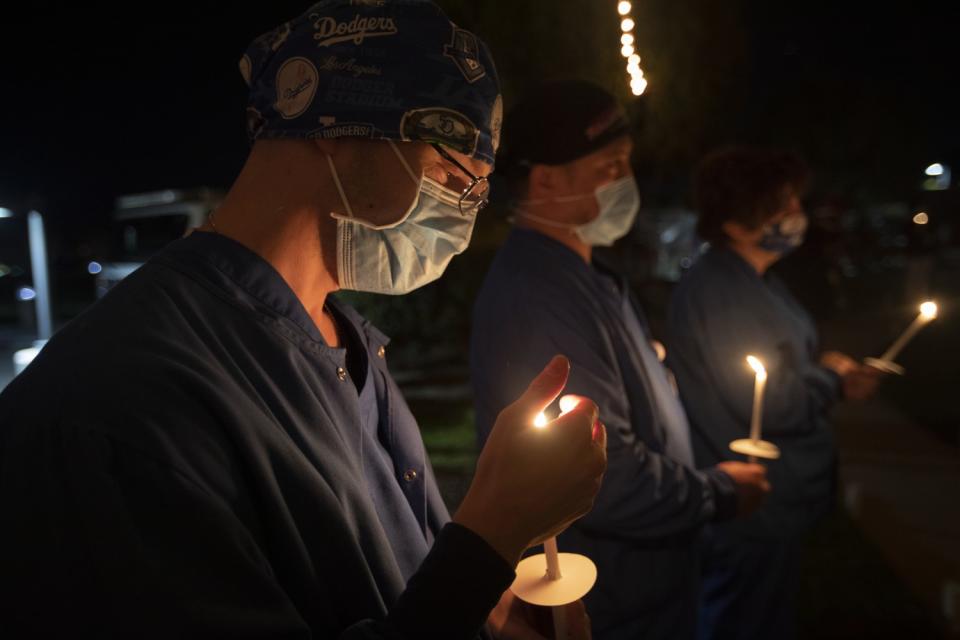 Hospital workers hold candles.