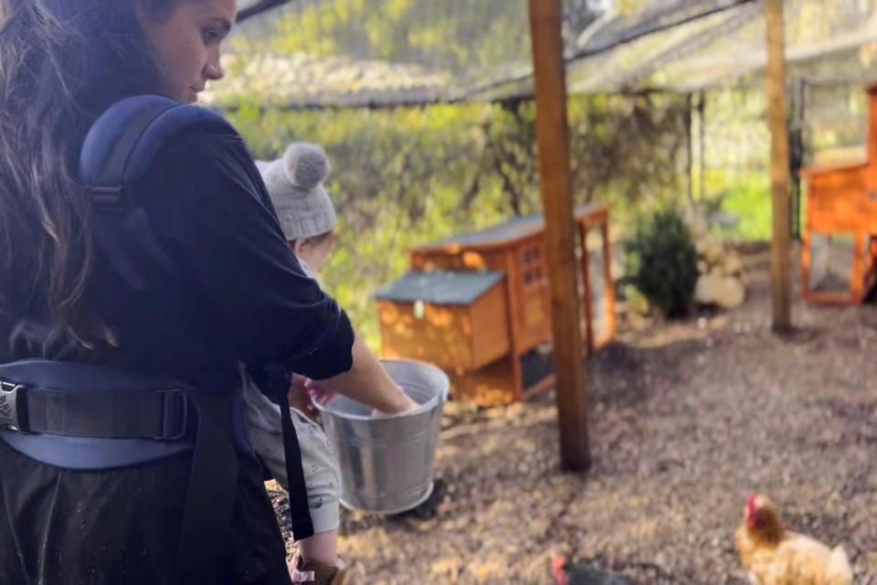 <p>The multi-tasking mom carries one of her kids while feeding the family chickens. </p>