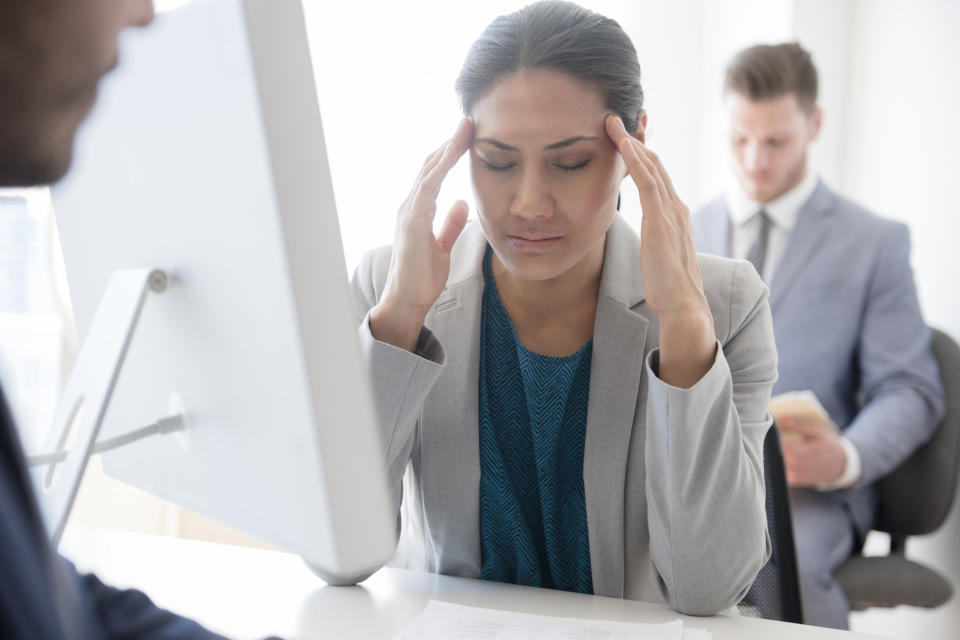 A woman massaging her temples at her desk