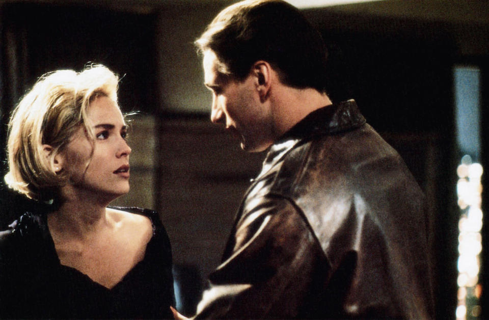 Sharon Stone and Billy Baldwin in a dramatic scene, with Stone looking concerned and Baldwin wearing a leather jacket, seemingly engaged in a serious conversation