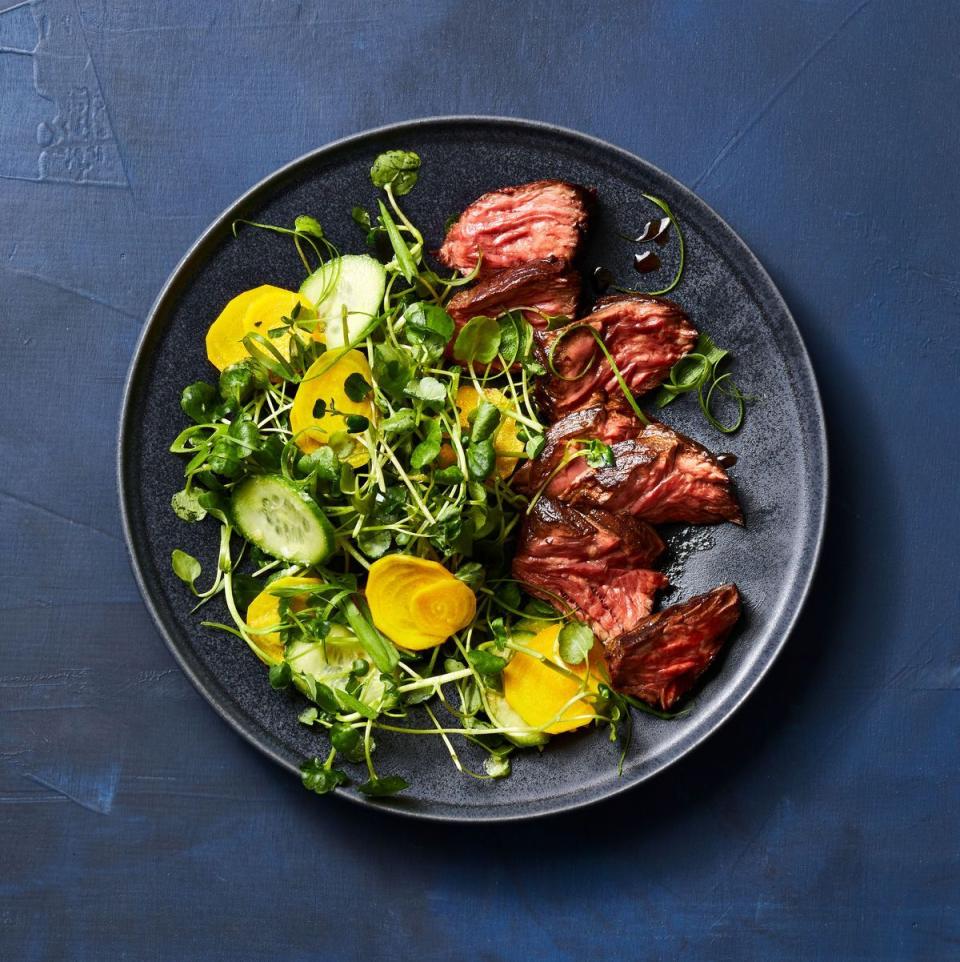 steak with pickled veggies and salad on a black plate