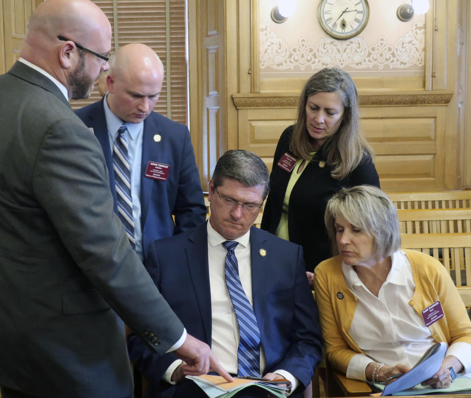 Kansas state Rep. Chris Croft, seated center, R-Overland Park, goes over a summary of a proposed $18.4 billion budget with colleagues after a meeting of GOP lawmakers, Friday, May 3, 2019, at the Statehouse in Topeka, Kan. Meeting with Croft, are from left, Reps. Stephen Owens, R-Hesston; Adam Thomas, R-Olathe; Kellie Warren, R-Leawood, and Barbara Wasinger, R-Hays, (AP Photo/John Hanna)