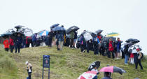 Spectators under umbrellas watch a during a practice round for the British Open Golf Championships at the Royal Liverpool Golf Club in Hoylake, England, Tuesday, July 18, 2023. The Open starts Thursday, July 20. (AP Photo/Jon Super)