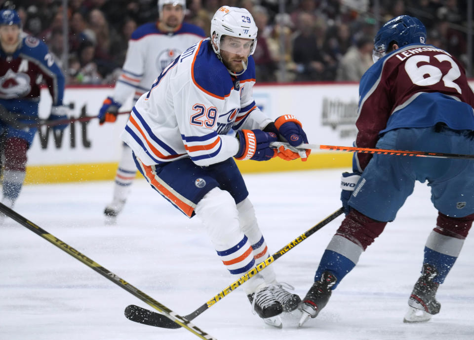 Edmonton Oilers center Leon Draisaitl, left, pursues the puck as Colorado Avalanche left wing Artturi Lehkonen defends during the second period of an NHL hockey game Sunday, Feb. 19, 2023, in Denver. (AP Photo/David Zalubowski)