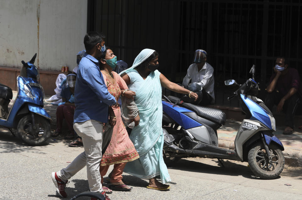 A family wails after identifying the body of their relative who died of COVID-19 outside a mortuary, in New Delhi, India, Monday, April 19, 2021. India's health system is collapsing under the worst surge in coronavirus infections that it has seen so far. Medical oxygen is scarce. Intensive care units are full. Nearly all ventilators are in use, and the dead are piling up at crematoriums and graveyards. Such tragedies are familiar from surges in other parts of the world — but were largely unknown in India. (AP Photo/Manish Swarup)